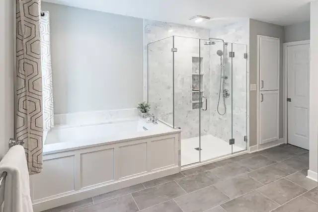 Bathroom remodel with a paneled soaking tub, frameless glass shower with marble tile and gray tile floor