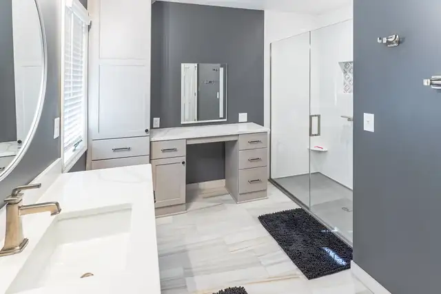 Bathroom remodel with a built-in makeup vanity, gray accent wall and glass walk-in shower