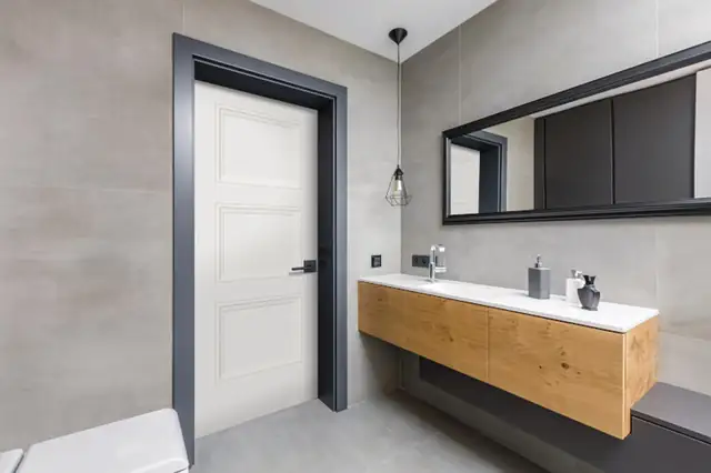 Modern bathroom with a floating oak vanity, long black-framed mirror and large-format gray tile