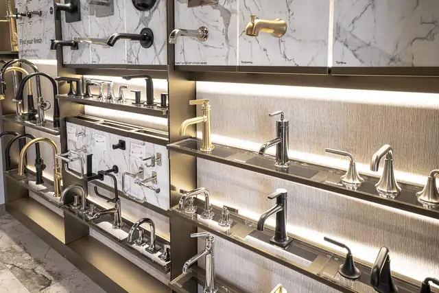 Lit display wall of faucets and fixtures in brass, black and chrome finishes at a Callen Design Center